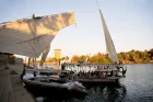 Wooden felucca sailing through the Nile River in Aswan Egypt during a scenic sightseeing experience
